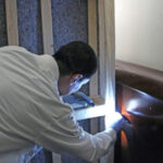 Colorado Pest Management technician with flashlight looking behind wall