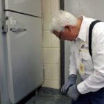Commercial pest inspection in front of a refrigerator
