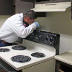 Checking behind the oven during a residential pest control inspection