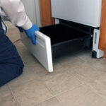 Checking under the oven during a residential pest control inspection