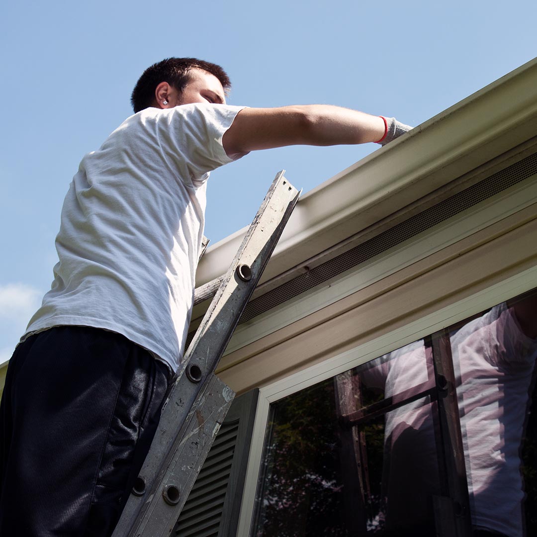 Man cleaning roof gutters
