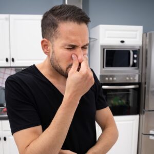 man experiencing foul odor in kitchen