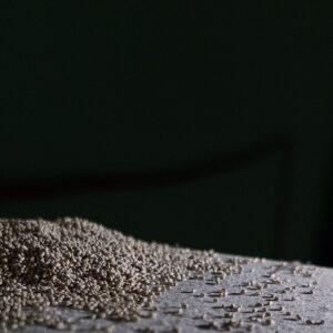 A pile of small, brown, granular frass pellets accumulated on a flat surface in dim lighting.
