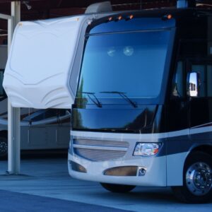 The front exterior of a large, black and grey motorhome parked alongside a white RV.