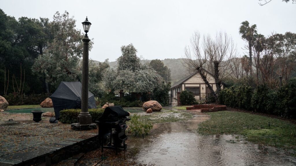 Rain pouring on a Denver home with a flooded lawn.